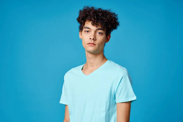 Guy with curly hair in blue t-shirt cropped view studio — Stock Photo, Image