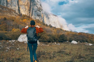 Sırt çantalı kadın dağlarda dinleniyor doğada ve sonbahar sarısı yapraklar üzerinde