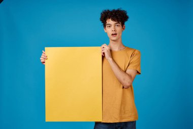 Kıvırcık saçlı, sarı saçlı adam. Poster modeli, mavi arka plan reklamı.