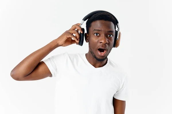 Homem emocional de aparência africana em fones de ouvido música amante luz fundo — Fotografia de Stock