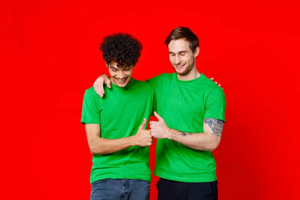Due amici che si abbracciano in magliette verdi comunicazione del team di amicizia — Foto Stock