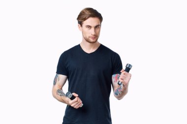 Elinde dambıllar olan erkek sporcu arka planda hafif bir kesim manzarası var.