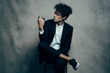 Spor ayakkabılı, tişörtlü, elinde kamera tutan bir adam.