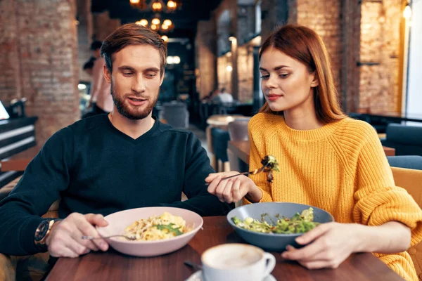 Um homem e uma mulher estão sentados em uma mesa em uma refeição de restaurante deliciosa comida que serve pratos — Fotografia de Stock