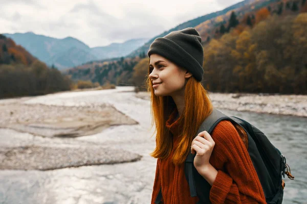 Viajante feliz com uma mochila em um chapéu e uma camisola nas montanhas perto do rio — Fotografia de Stock