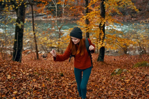 Frau im Pullover mit Rucksack ruht im Herbst in einem Park in der Nähe des Flusses in der Natur — Stockfoto