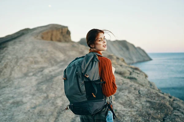 Frau in rotem Pullover in den Bergen über die Natur und einen Rucksack auf dem Rücken blauer Meereshimmel Herbst — Stockfoto