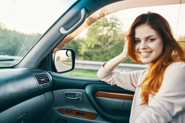 Mulher feliz com cabelo vermelho no banco da frente do carro tocando o rosto com as mãos cortadas vista — Fotografia de Stock