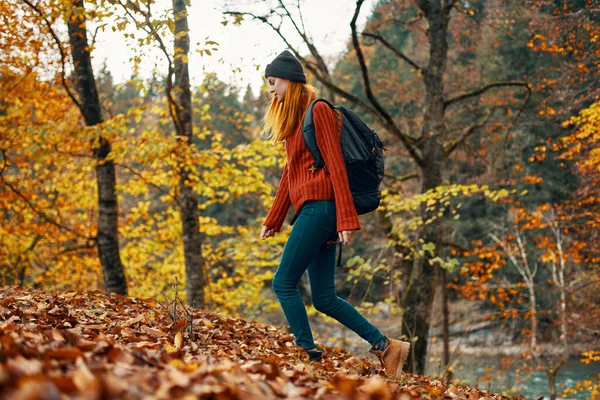 Žena cestovatel s batohem procházky v parku na podzim v přírodě boční pohled — Stock fotografie