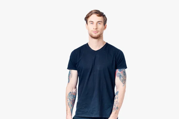 Homem desportivo em uma camiseta azul com tatuagens em seus braços em um fundo branco Copiar espaço — Fotografia de Stock