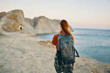 Sırtında sırt çantasıyla dağlarda gezen bir gezgin kıyıya gider ve deniz yakınlardadır.