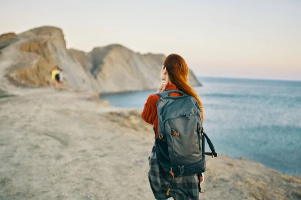 Мандрівник в горах з рюкзаком на спині йде в сторону, а море поруч — стокове фото