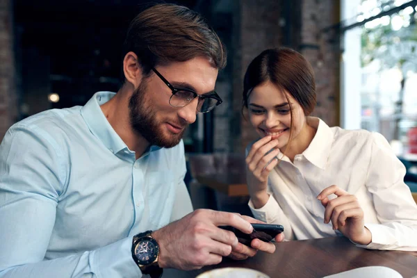 Alegre hombre y mujer están sentados en un café en la mesa de trabajo de tecnología de la comunicación —  Fotos de Stock