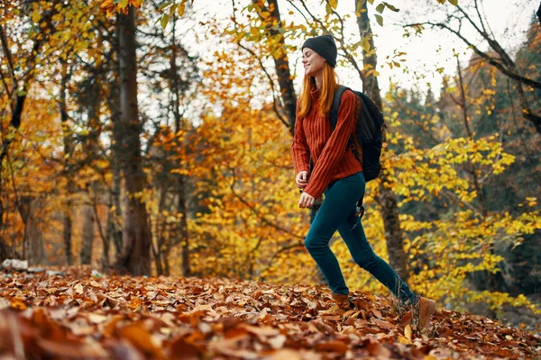 Mooie vrouw met een rugzak in het park op natuur landschap gevallen bladeren onderste uitzicht — Stockfoto