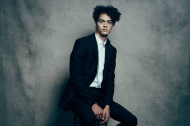 Yakışıklı, kıvırcık saçlı, kendine güvenen bir adam.