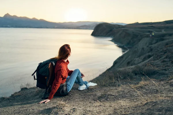 Мандрівник з рюкзаком дивиться на захід сонця на море в горах — стокове фото