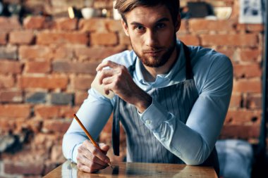 Kafede tezgahın arkasında barmen ve mavi gömlekli önlük menüsü.