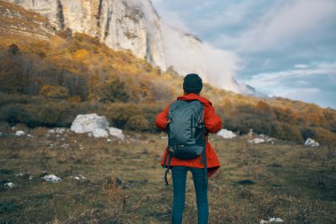Kırmızı ceketli, sonbaharda açık hava şapkalı bir kadın manken.