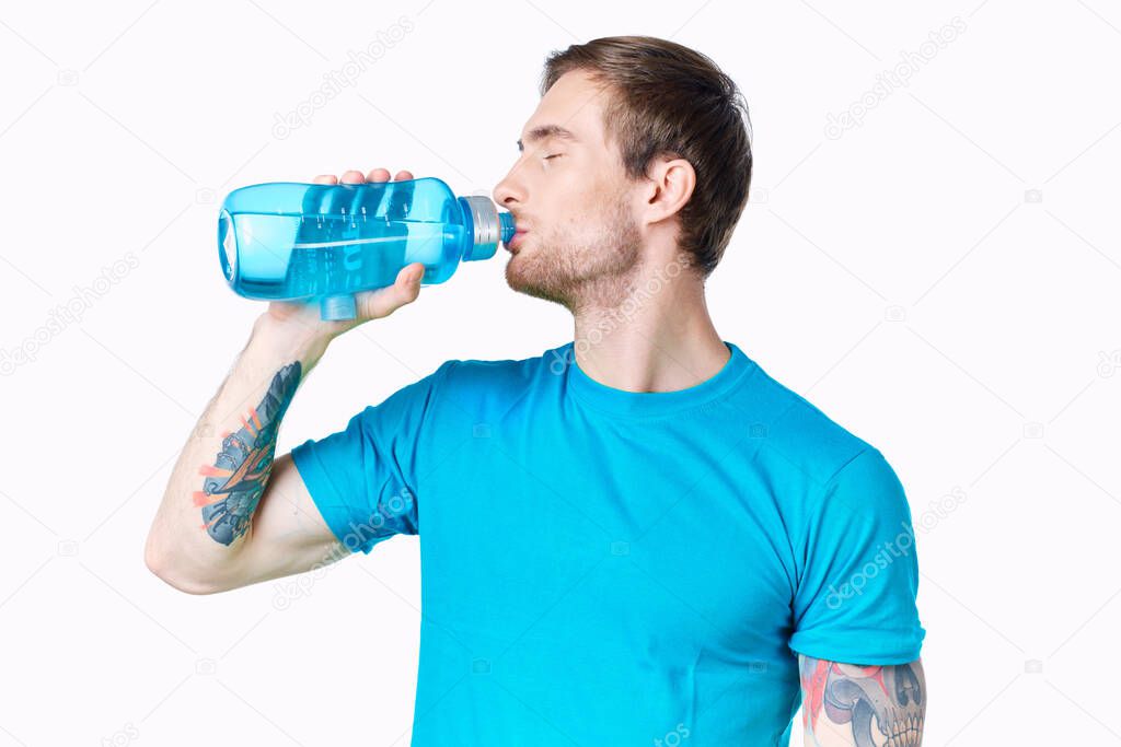 guy athlete drinks water from a bottle on a white background and a blue t-shirt
