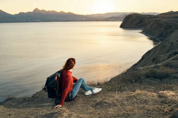 Il viaggiatore siede sulla sabbia in montagna e si rilassa vicino al mare al tramonto — Foto Stock