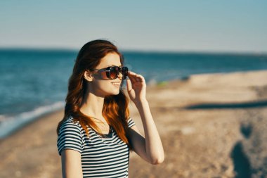 Gözlüklü ve açık havada el kol hareketi yapan kadın.