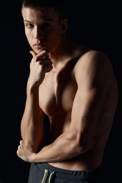 Αθλητικός τύπος με φουσκωμένο μπράτσο μυς σε μαύρο φόντο πορτρέτο περικοπεί άποψη — Φωτογραφία Αρχείου