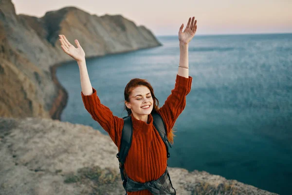 happy woman with raised up arms walks on the beach near the sea and high mountains travel top view