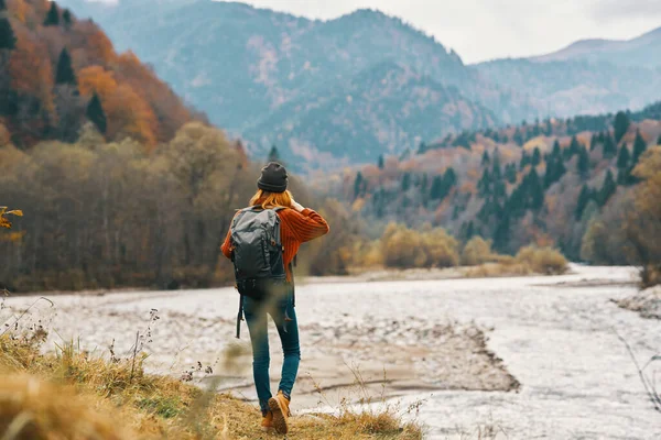 Mulher viajante com uma mochila em pleno crescimento na margem do rio nas montanhas — Fotografia de Stock