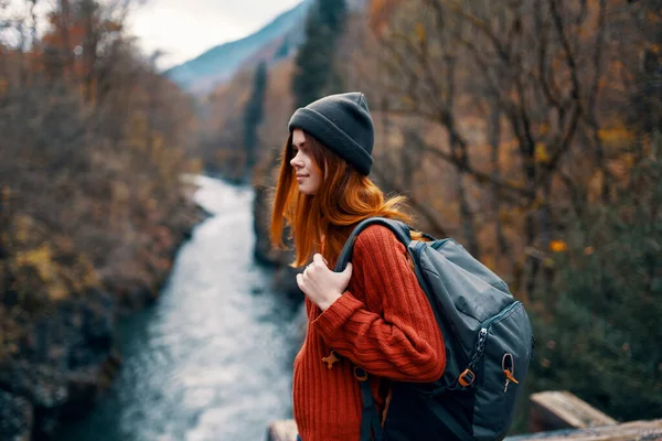 Mujer excursionista en el bosque de otoño en el puente cerca del viaje por el río —  Fotos de Stock