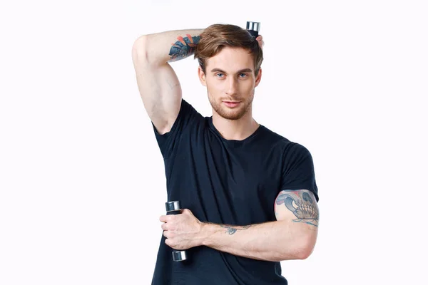 Tipo con mancuernas sostiene su mano detrás de su cabeza y fondo claro negro camiseta deporte fitness — Foto de Stock