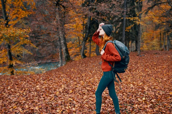 Glücklich Reisenden Frau mit Rucksack Spaziergänge durch den herbstlichen Park in der Natur in der Nähe der Flusslandschaft hohe Bäume Pullover — Stockfoto