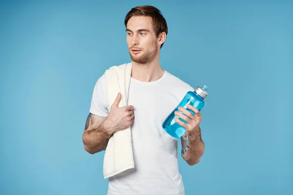 Uomo sportivo con tatuaggi sulle braccia bottiglia d'acqua energia sfondo blu — Foto Stock