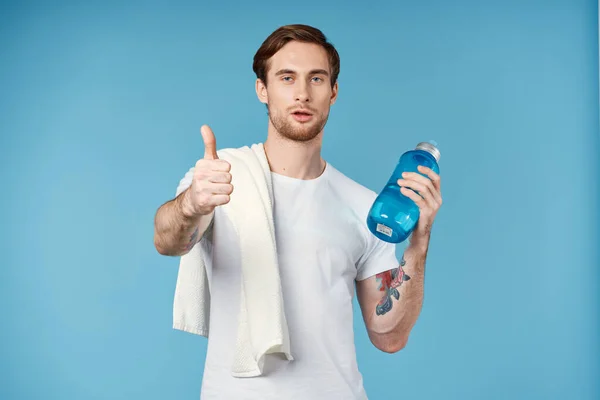 Sporty uomo mostrando pollice in su bottiglia d'acqua asciugamano sulla spalla ritagliato vista sfondo blu — Foto Stock