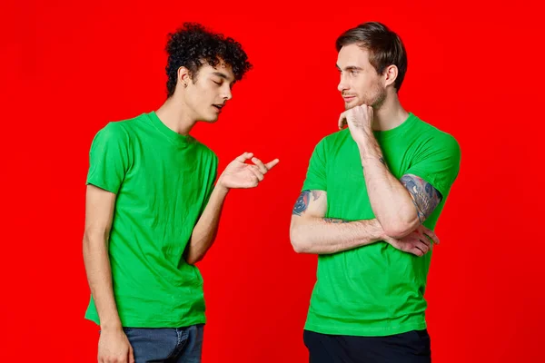 녹색 티셔츠를 입은 두 남자가 나란 히서 서 의사소통을 하고 있다 — 스톡 사진