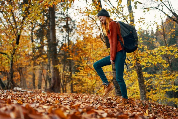 Mooie vrouw met een rugzak in het park op natuur landschap gevallen bladeren onderste uitzicht — Stockfoto