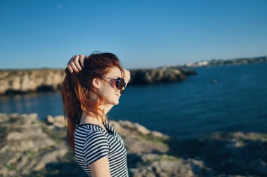 Mutlu kadın tişörtü saçlarına değiyor ve dağlarda rahatlıyor.