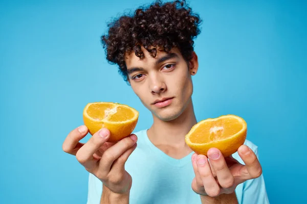 Hombre con pelo rizado sosteniendo naranjas fruta fondo azul — Foto de Stock