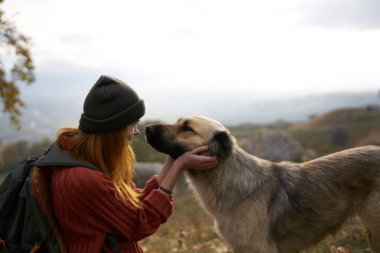 Açık havada gezen bir köpeğin yanında neşeli bir kadın.