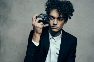 Gri arka planda kameralı fotoğrafçı ve ceket kıvırcık gömlek modeli.