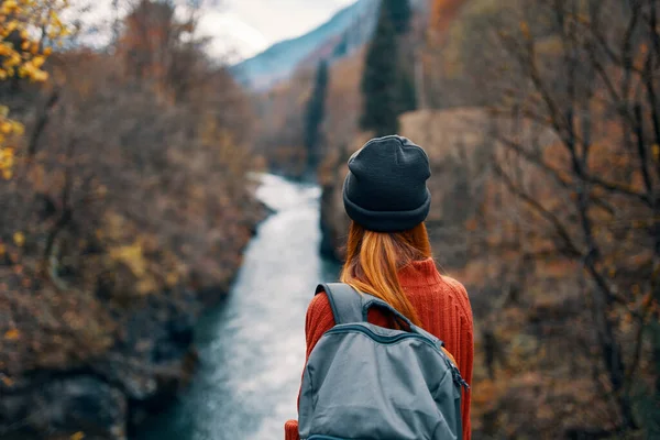 Kvinna med ryggsäck i naturen på bron nära floden bergen äventyr — Stockfoto