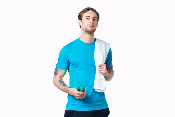 Homem com halteres em mãos toalha no ombro treino fitness fundo luz — Fotografia de Stock