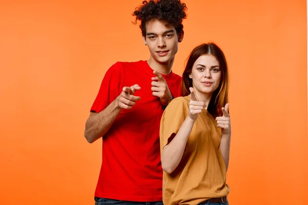 Mec et fille dans coloré t-shirts amusant studio fond orange — Photo