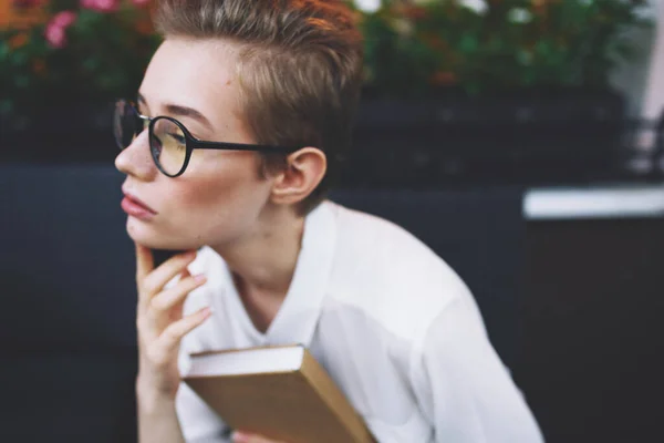 Воспитательная женщина в очках с книгой за столом в кафе — стоковое фото