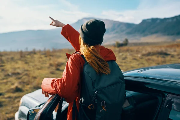 Kvinna nära bilar gester med händerna på naturen i bergen höst ryggsäck resor turism — Stockfoto