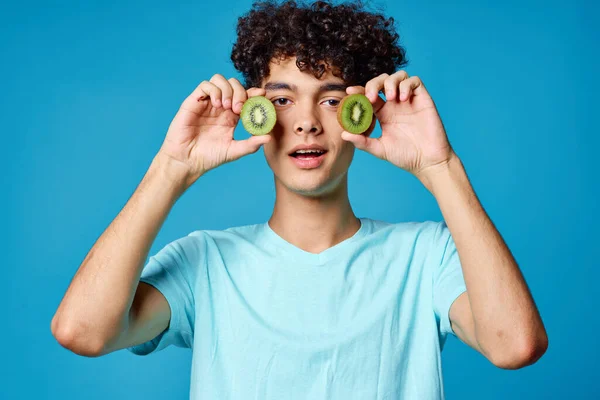 Hombre con el pelo rizado kiwi cerca de la cara fondo azul vista recortada — Foto de Stock