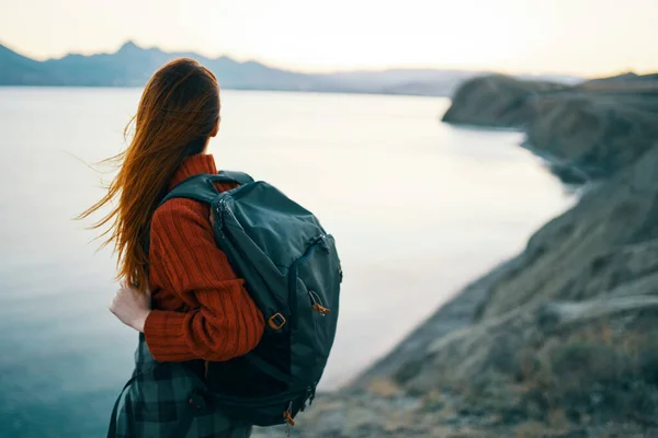Жінка в червоному светрі з рюкзаком і подорожуючим туризмом морські гори — стокове фото
