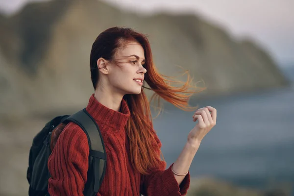 Viaggiare con uno zaino sulla schiena in maglione rosso in montagna vicino al mare nella natura — Foto Stock