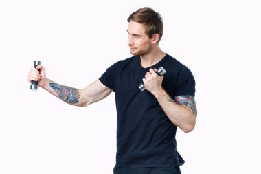 Dambıllı sporcu, arka planda hafif bir iç görünüş ile spor yapıyor.