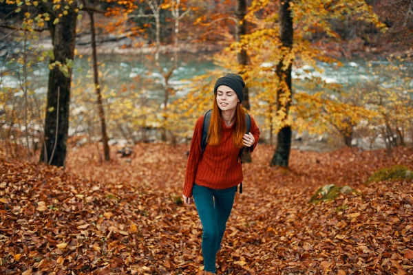 Cestování turistika žena ve svetru a džíny v podzimním lese v blízkosti horské řeky — Stock fotografie