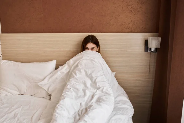 woman woke up early in the morning under the covers in bed